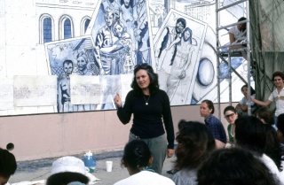 Judith F. Baca, Photograph of The Great Wall of Los Angeles A view of Judy Baca and mural-makers meeting at the 1940’s section titled “David Gonzalez” in progress. Photograph courtesy of SPARC Archive