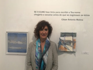 La artista Isabel Pintado entre uno se sus paisajes y un libro intervenido. Cortesía de la Casa de Galicia