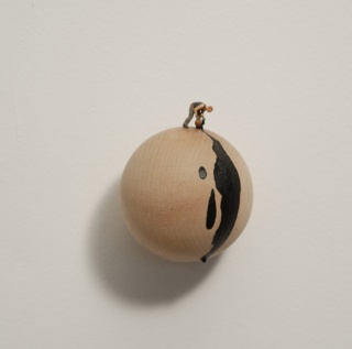 Black Drip (2009). Liliana Porter. Instalación con esfera de madera, figura metálica y pintura acrílicawooden sphere, metal figurine, and acrylic paint wall installation