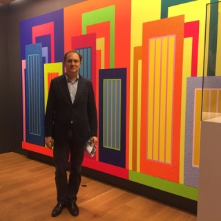 Carlos Durán posando delante de una obra de Peter Halley. Cortesía de Galería Senda